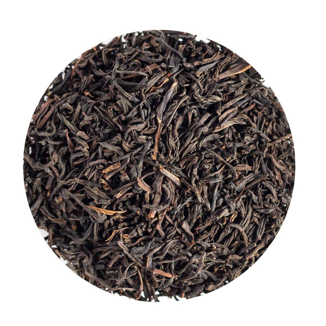 Close-up of dark brown tea leaves on a white background