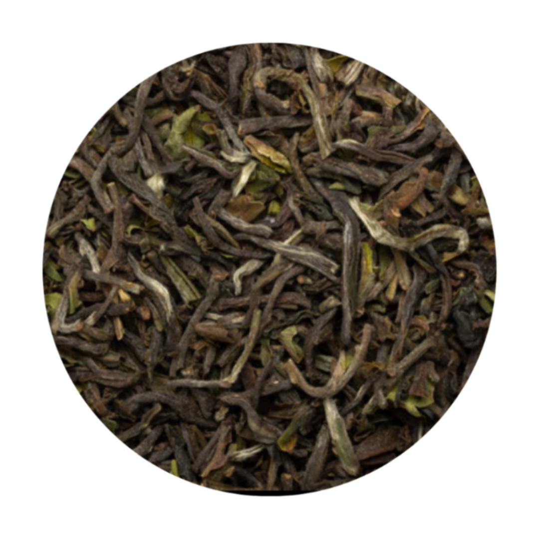 A circular close-up of loose-leaf tea leaves, showing dark brown and green rolled buds and stems, isolated on a white background.