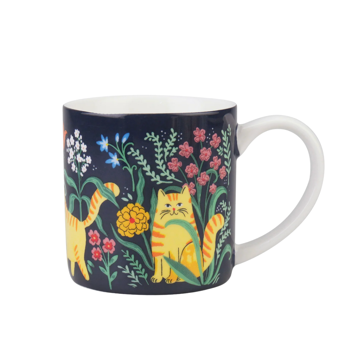 Navy mug with orange cat and floral design on a white background