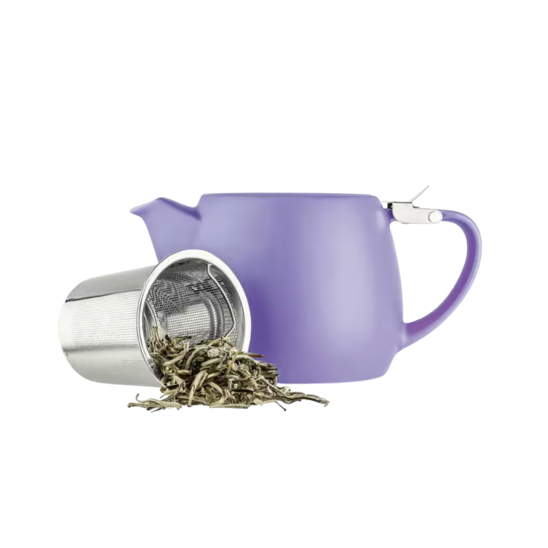 Purple teapot with a tea infuser containing loose tea leaves on a white background