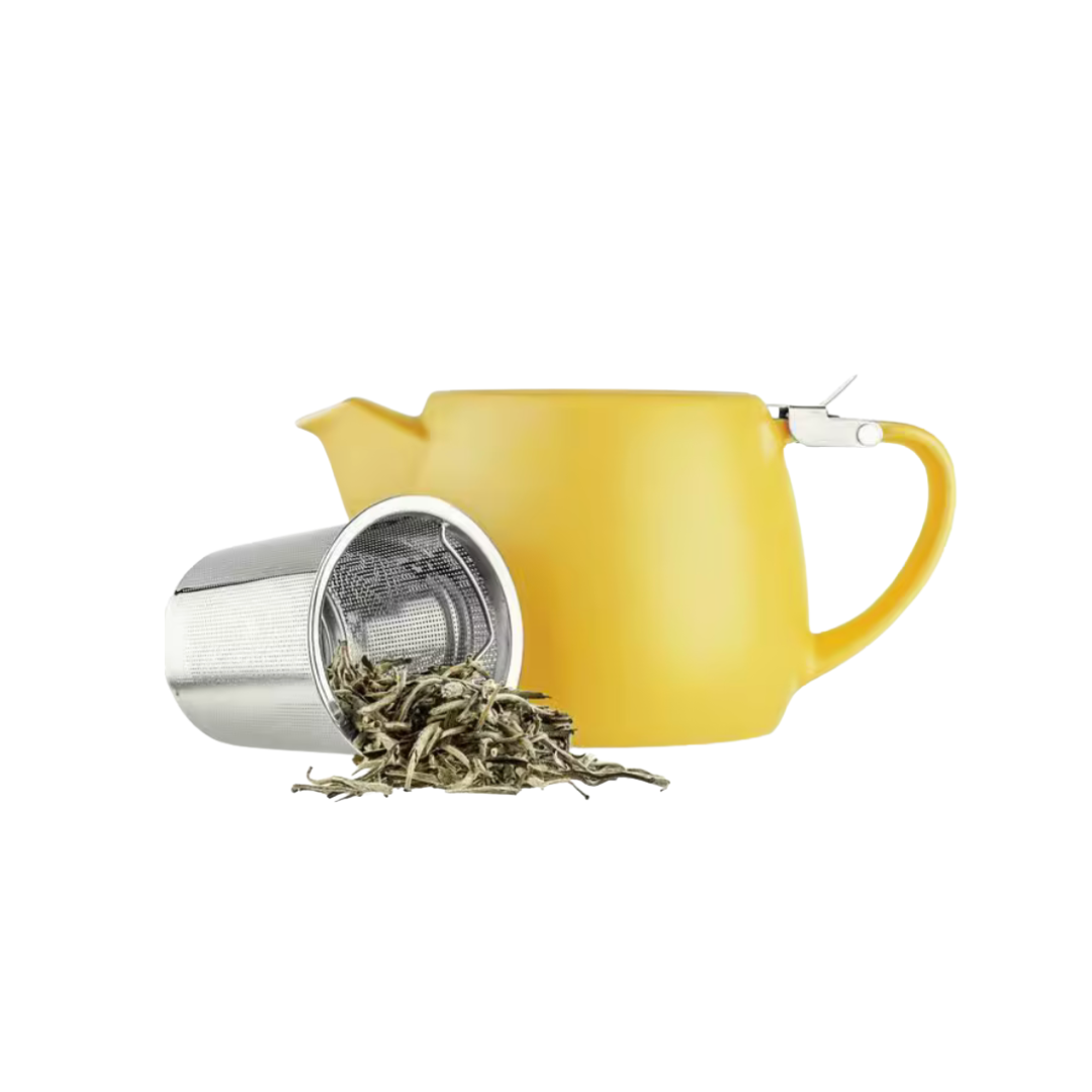 Yellow teapot with a tea infuser and loose tea leaves on a white background