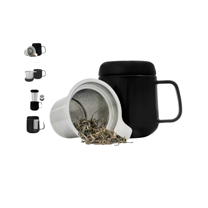 Black mug with lid and infuser basket containing tea leaves on a white background