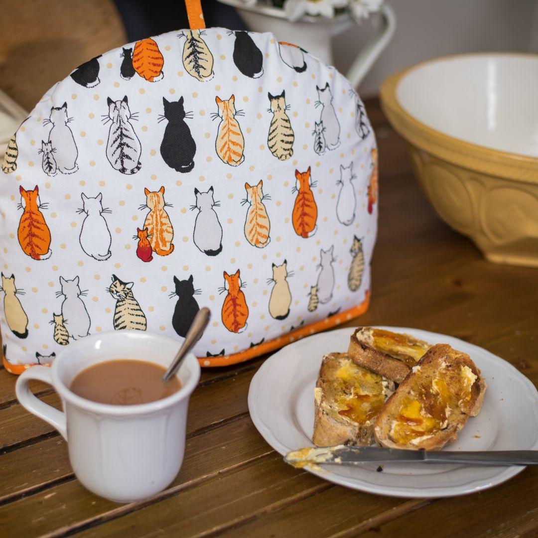 Cat Print Tea Cosy cover over a teapot at the breakfast table.